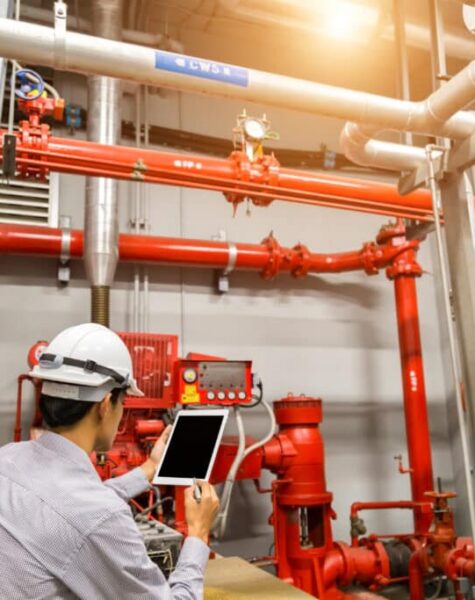 Engineer with tablet check red generator pump for water sprinkler piping and fire alarm control system.
